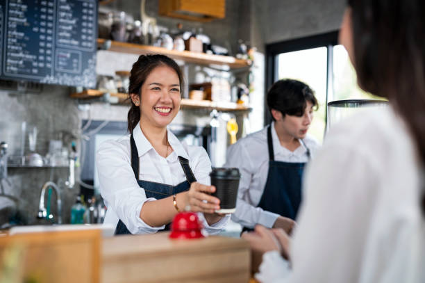 shot of a female barista serving a cup of coffee to a customer in a cafe counter. small business owner, service mind and customer service. - junk food stock pictures, royalty-free photos & images