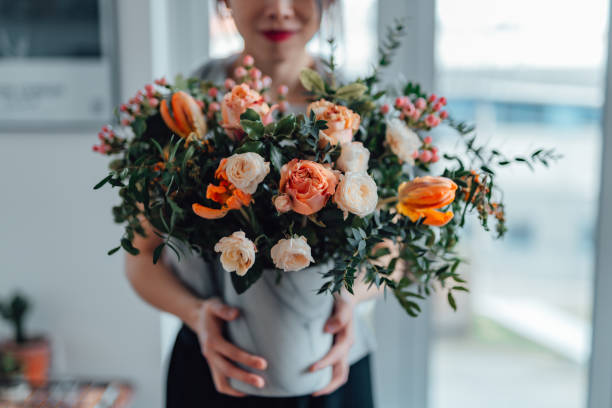 shot of an unrecognisable woman covering her face with flowers in living room - home decoration stockfoto's en -beelden