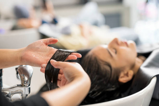 shot of relaxed customers getting a hair washed by beautician at the beauty salon. focus hand of hairstylist washed of customer hair. hair treatment, hair care. beauty hair salon business. - hairstyle fotografías e imágenes d
