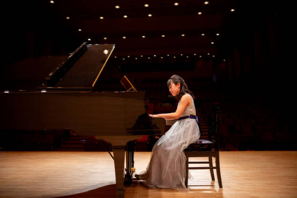 side view of teenage girl playing the piano in concert hall - concert stock pictures, royalty-free photos & images