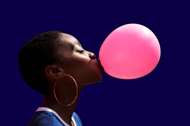 side view of young woman blowing balloon - food stock pictures, royalty-free photos & images