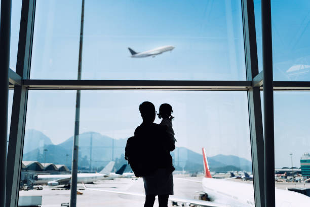 silhouette of joyful young asian father carrying cute little daughter looking at airplane through window at the airport while waiting for departure - travel stock pictures, royalty-free photos & images