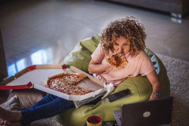 single woman watching online tv and eating pizza - junk food stock pictures, royalty-free photos & images