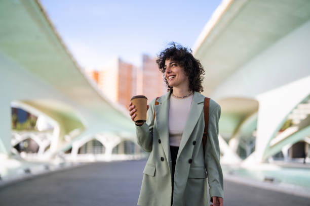 smart young female student looking away while holding coffee to go. - junk food stock pictures, royalty-free photos & images