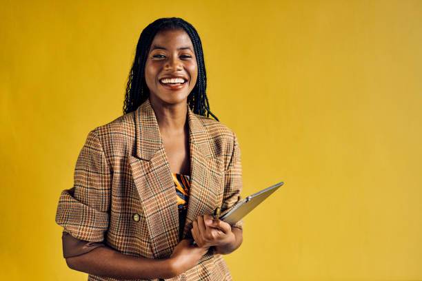 smiling african american businesswoman in a plaid blazer holding a tablet in a modern office. empowerment and professional growth in business concept - home decoration stock-fotos und bilder
