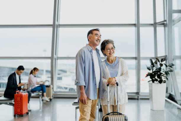 smiling asian senior couple tourists in airport - travel stock pictures, royalty-free photos & images