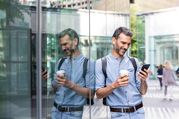 smiling businessman looking at the smartphone in the city, berlin, germany - junk food stock pictures, royalty-free photos & images