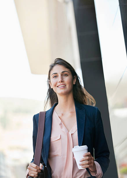 smiling businesswoman walking with coffee cup - junk food stock pictures, royalty-free photos & images