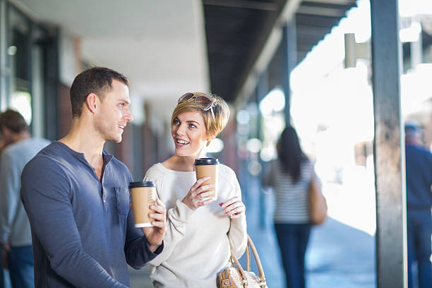 smiling couple with coffees to go - junk food stock pictures, royalty-free photos & images
