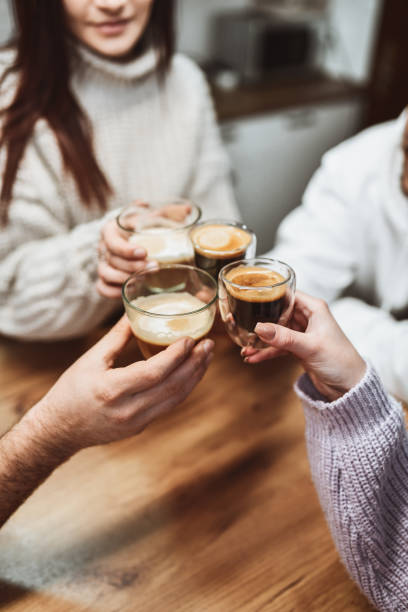 smiling friends making celebratory toast at home with different types of coffee - coffee stockfoto's en -beelden