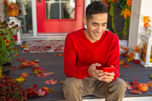 smiling man texting on front autumn porch - garden decoration stock pictures, royalty-free photos & images