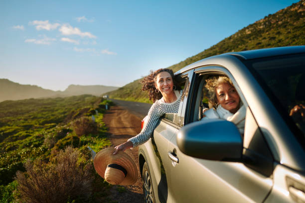 smiling mature women enjoying the scenic view during a road trip together - travel stock pictures, royalty-free photos & images