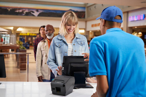 smiling woman buying tickets at counter in theater - junk food stock pictures, royalty-free photos & images