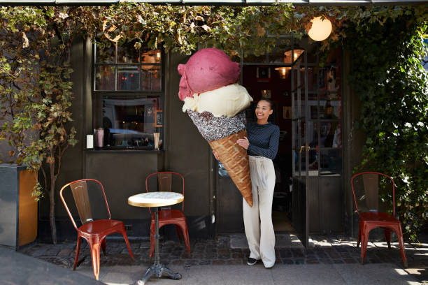 smiling woman carrying large ice cream cone at sidewalk cafe - food stock pictures, royalty-free photos & images