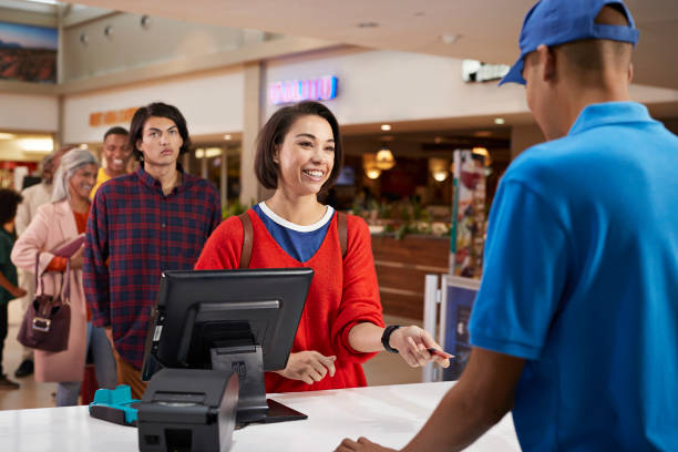 smiling woman paying for movie tickets - junk food stock pictures, royalty-free photos & images