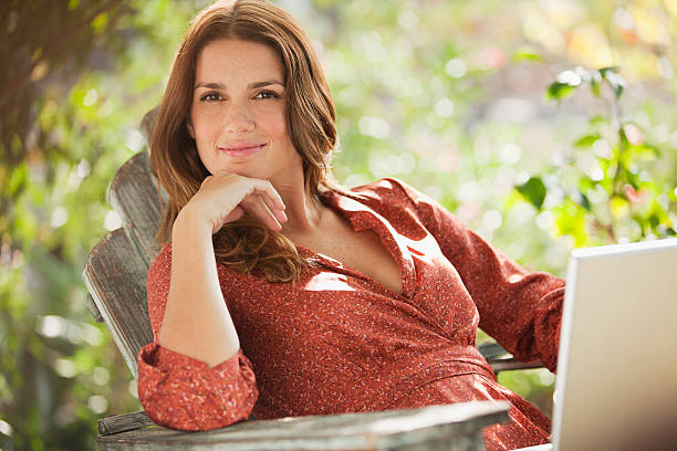 smiling woman using laptop outdoors - garden decoration photos et images de collection