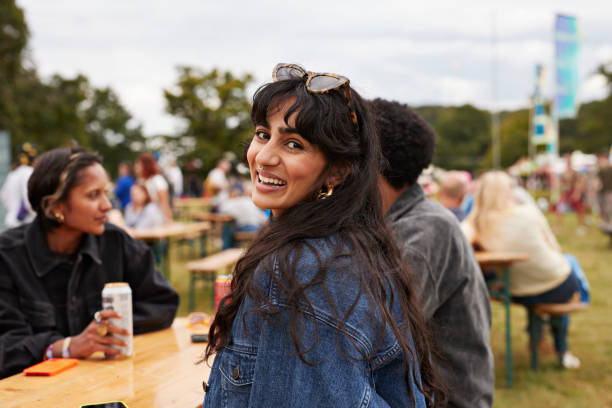 smiling woman wearing jacket sitting with friends - concert stock pictures, royalty-free photos & images