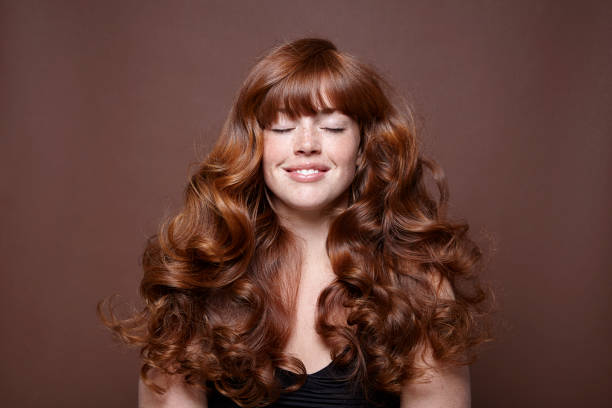smiling woman with windblown red long hair - hairstyle stockfoto's en -beelden