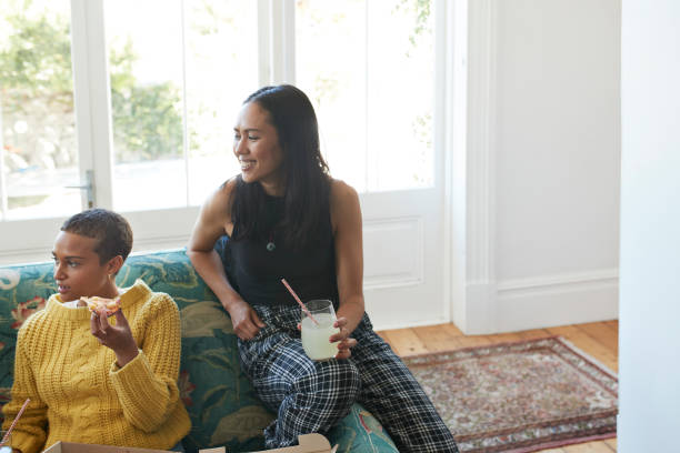 smiling young women with fresh pizza and drink - junk food stock pictures, royalty-free photos & images