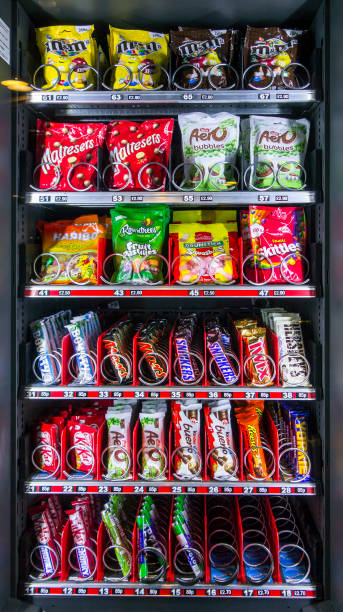 Snack vending machine / snack dispenser selling colourful sweets and chocolate bars in public place.