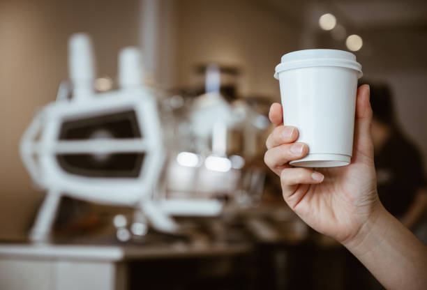 someone hand holding a paper cup of hot coffee in coffee shop. - junk food stock pictures, royalty-free photos & images