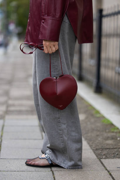 Sonia Lyson wears ballerinas and burgundy heart shaped bag Alaia, grey wide leg jeans Levis, leather shirt Gant on the way to Gmbh during the Berlin...