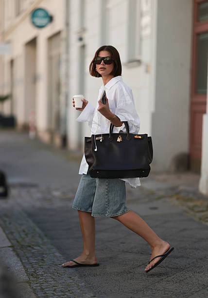 Sophia Geiss is seen wearing chunky silver hoop earrings, a silver nose ring, black aviator sunglasses from Vehla Eyewear, an oversized white...