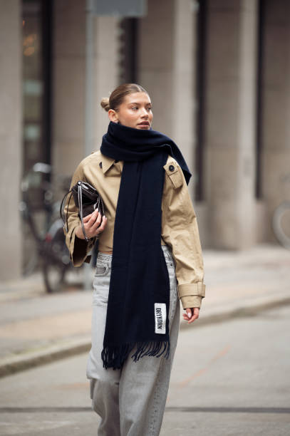 Sophia Geiss wears grey jeans, beige crop trench coat, black soft leather pouch bag and long black scarf during the Copenhagen Fashion Week...