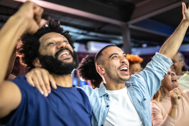 sports fans watching a match and celebrating at a bar - concert stock pictures, royalty-free photos & images