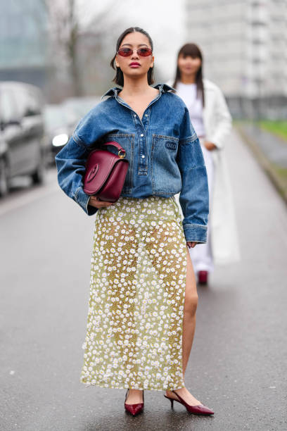 Steph Hui wears burgundy bordeaux oval Gucci sunglasses, silver earrings, navy blue oversized denim jean Gucci bomber jacket, a shiny burgundy...