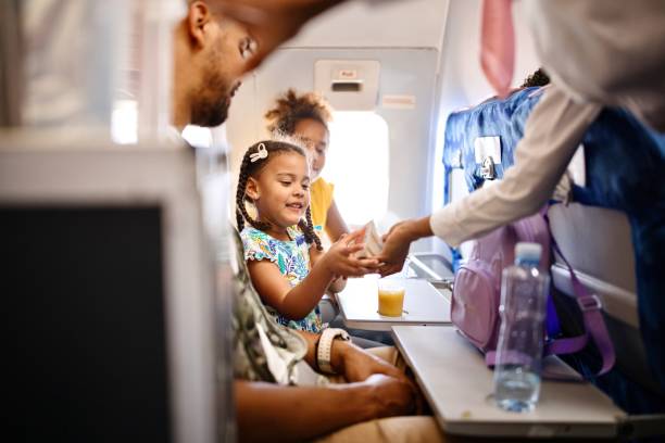 stewardesses serving food and drinks to family on the airplane during flight - food stock pictures, royalty-free photos & images