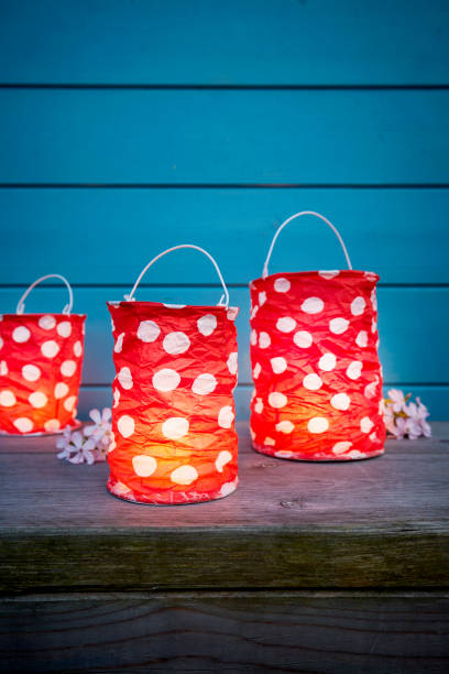 still life of dotted red paper lanterns for party decoration in front of blue wooden wall in the evening - garden decoration stock pictures, royalty-free photos & images