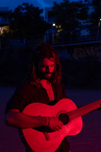 street musician playing guitar and singing at night - concert stock pictures, royalty-free photos & images