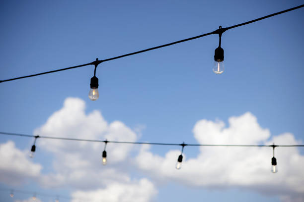 string lights against a blue sky with white puffy clouds - garden decoration stock pictures, royalty-free photos & images