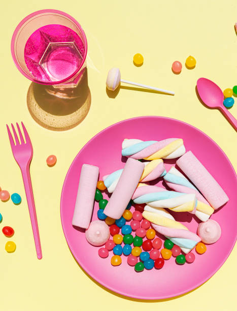 studio shot of glass of water and plastic plate filled with various sweets - junk food stock pictures, royalty-free photos & images