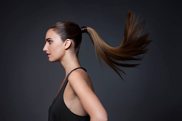 studio shot of young woman tossing hair - hairstyle photos et images de collection