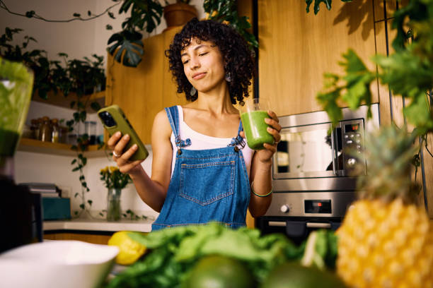 stylish home chef researches vitamin rich recipes on mobile for balanced nutrition plan - food stock pictures, royalty-free photos & images