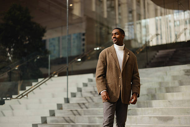stylish man in brown jacket standing on modern urban steps outdoors - fashion stock pictures, royalty-free photos & images