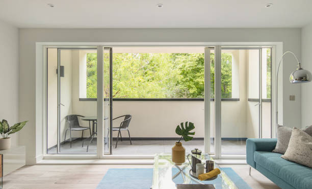 stylish show home living room of a contemporary apartment with open sliding doors onto a balcony - home decoration stock pictures, royalty-free photos & images