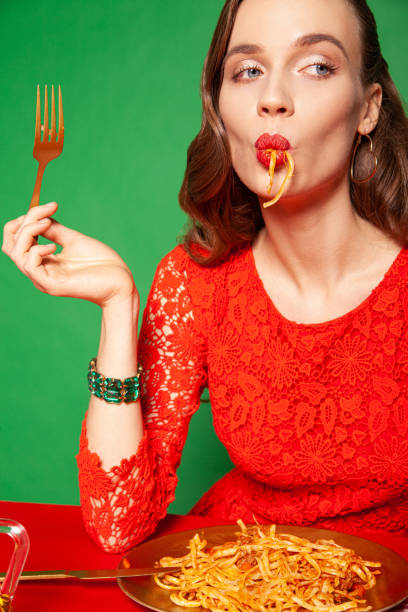 stylish woman in red dress eating spaghetti - food stockfoto's en -beelden