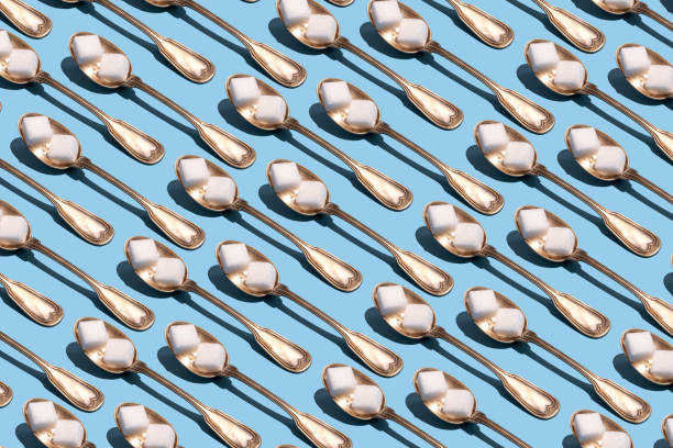 sugar cubes in metallic spoons on the blue background - junk food stock pictures, royalty-free photos & images