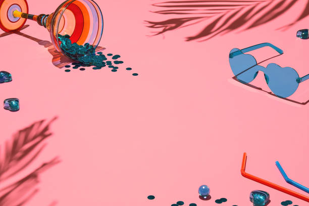 summer flat lay - tropical palm shadows, heart shaped sunglasses and cocktail glass filled with confetti on soft pink background - fashion stock pictures, royalty-free photos & images