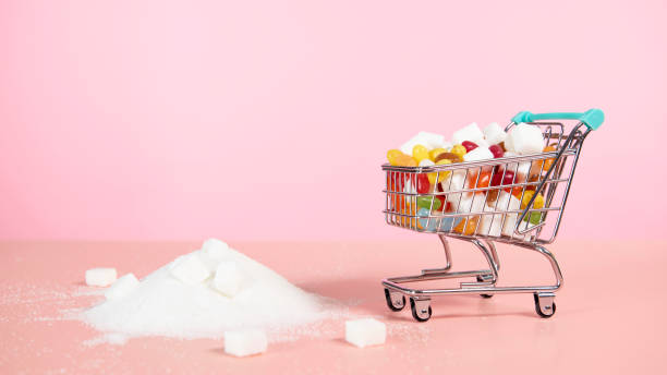 supermarket trolley with candy next to pile of sugar - junk food stock pictures, royalty-free photos & images