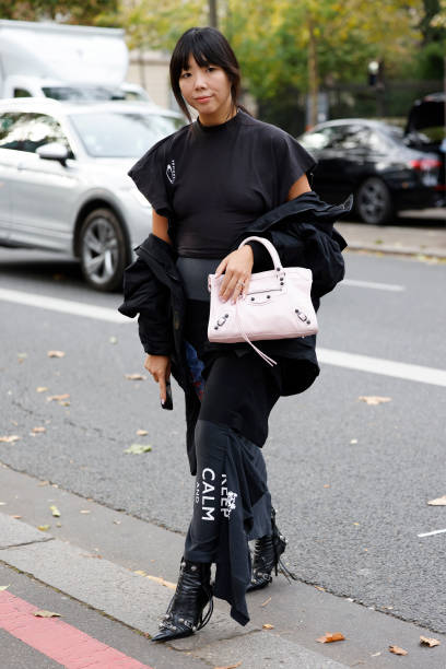 Susanna Lau wears black short sleeves top, white Balenciaga bag, black printed long skirt, black jacket, black boots, outside Rokh, during Womenswear...