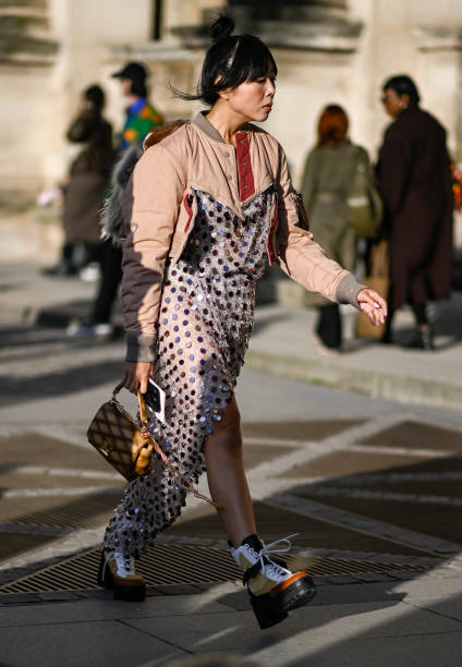 Susie Lau is seen wearing a light pink and gray jacket, sequin sheer Louis Vuitton dress, tan Louis Vuitton bag and Louis Vuitton high top sneakers...