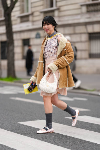 Susie Lau wears dark gray polo sleeveless Miu Miu shirt, light pink dark purple sequin sleeveless Miu Miu midi dress, light brown cream faux fur...