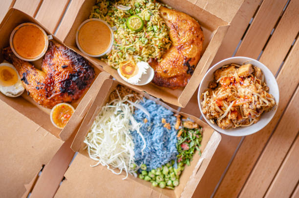 table top view malaysian food nasi kerabu, nasi ulam and ayam percik in recycled paper container with sauce - junk food stock pictures, royalty-free photos & images