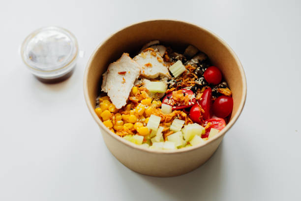 take away food in brown paper craft plate. chicken, corn, tomatoes, celery and sause. take away delivery. environment protection - junk food stock pictures, royalty-free photos & images