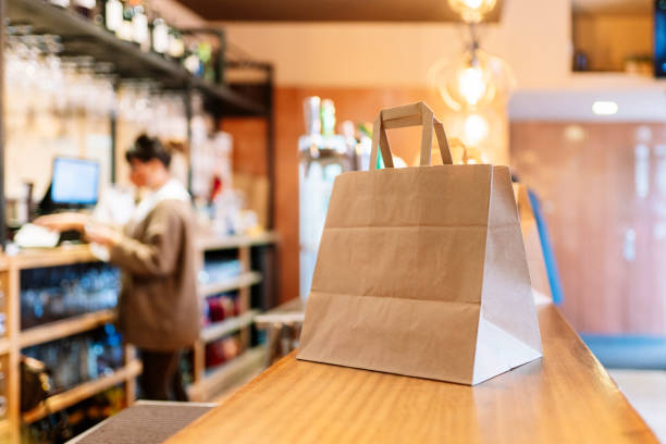 take out food kept in brown paper bag on bar counter during pandemic - junk food stock pictures, royalty-free photos & images