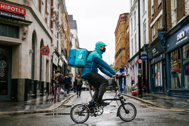 Takeaway food courier, working for Deliveroo, operated by Roofoods Ltd., cycles past food outlets in the Soho district of London, U.K., on Friday,...